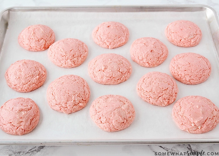 cooked pink strawberry cake mix cookies on a baking sheet without any frosting