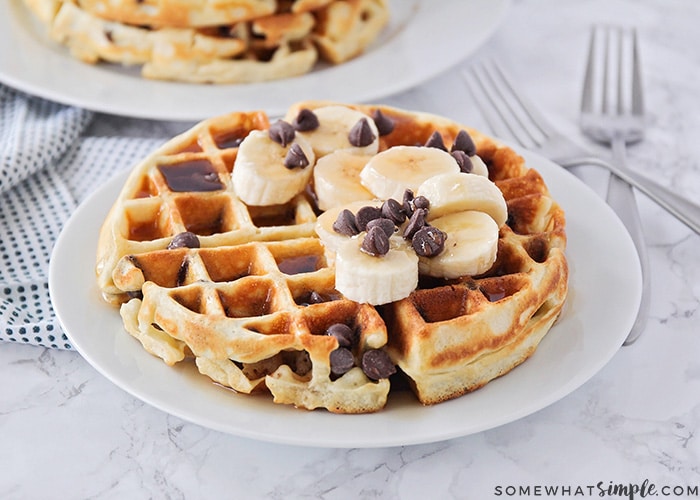 fluffy chocolate chip waffles topped with syrup, bananas and chocolate chips