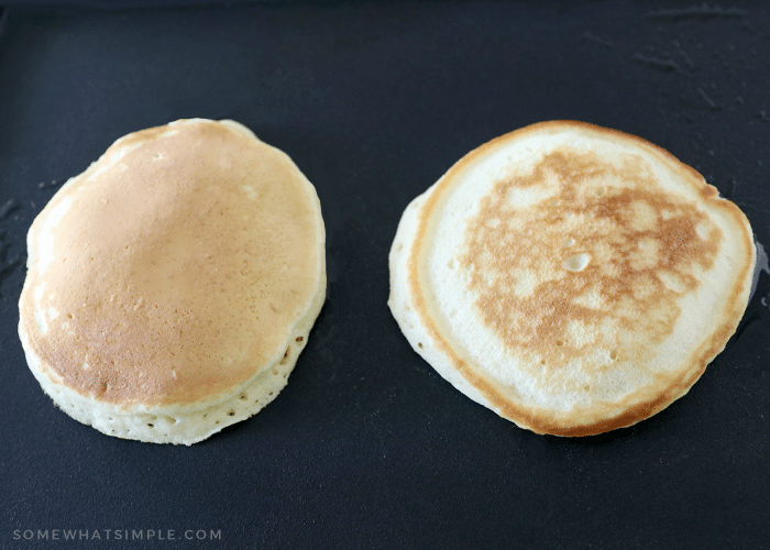 two pancakes side by side on a black griddle