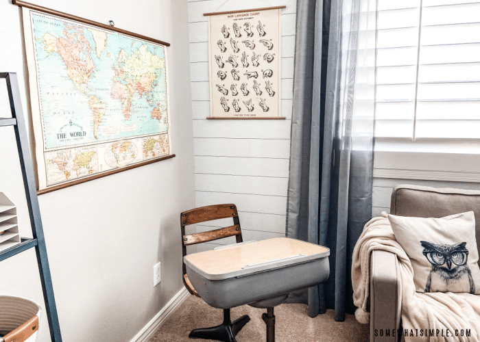 vintage desk in the corner of a room with a sign language and world map poster
